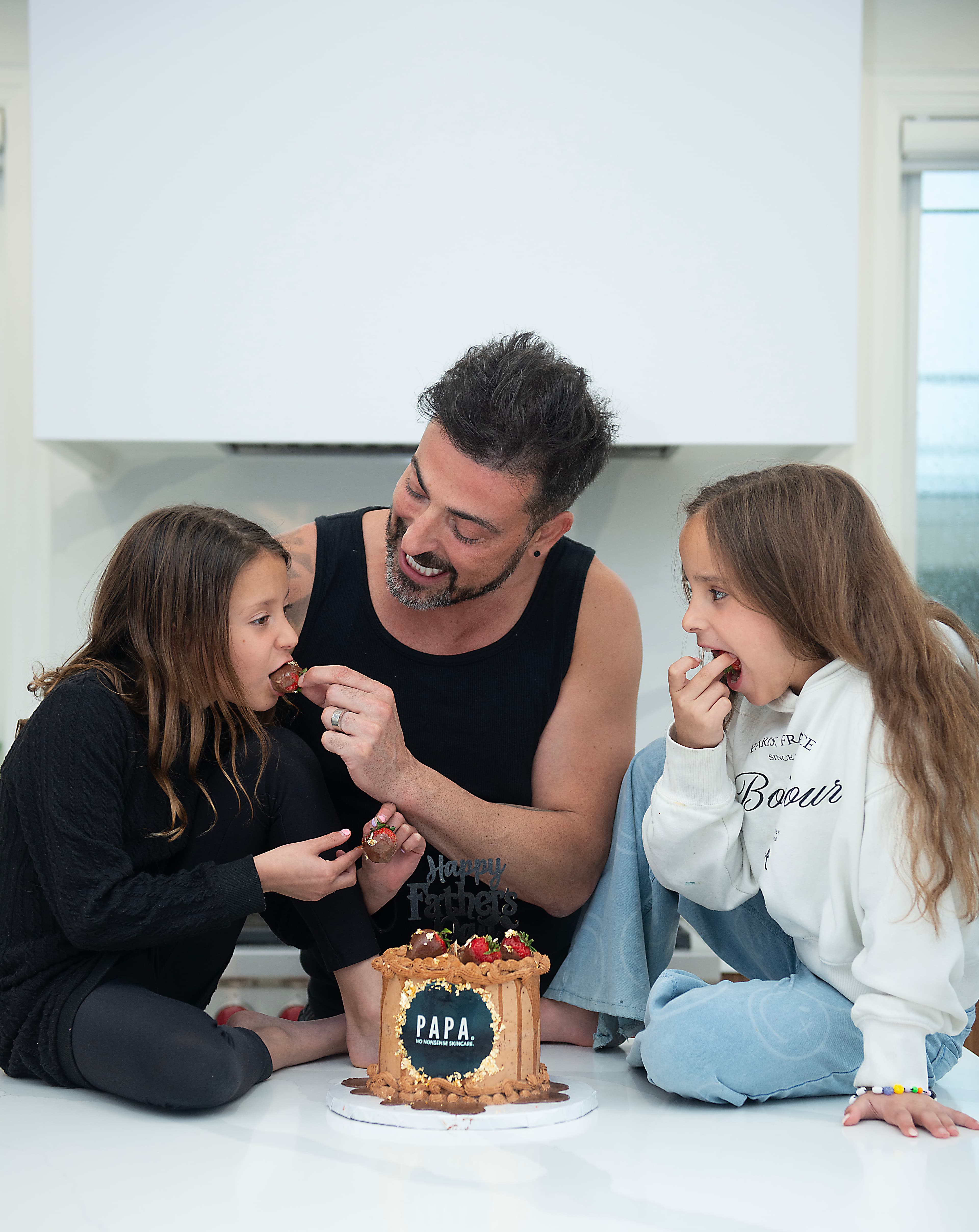 A dad and his two daughters sharing the PAPA Father's Day cake