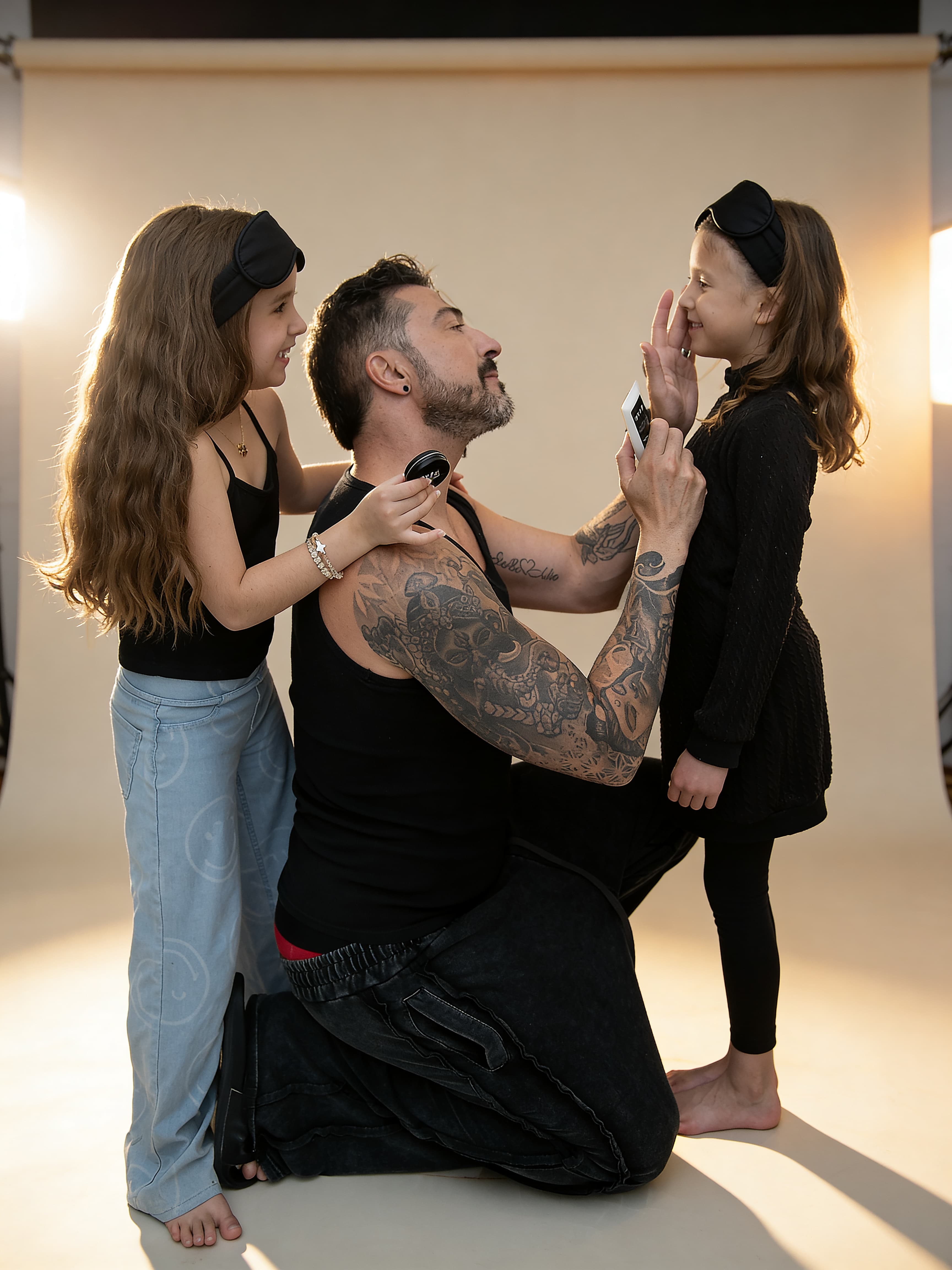 A dad sharing a tender skincare moment with his two daughters